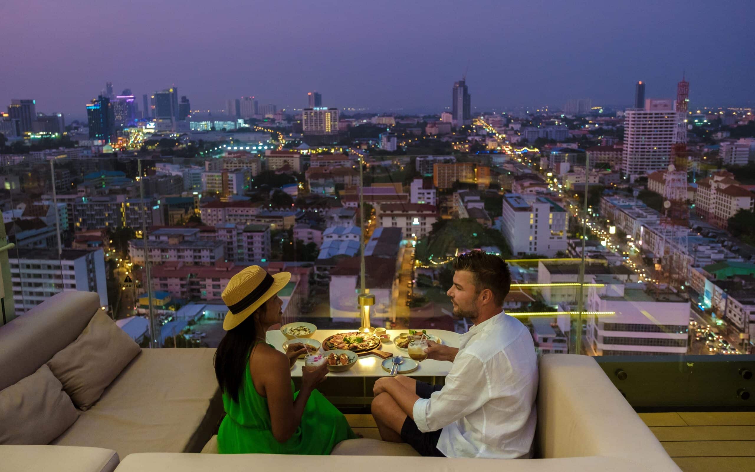 Paar beim Abendessen auf einer Rooftop-Bar mit Blick über die Stadt