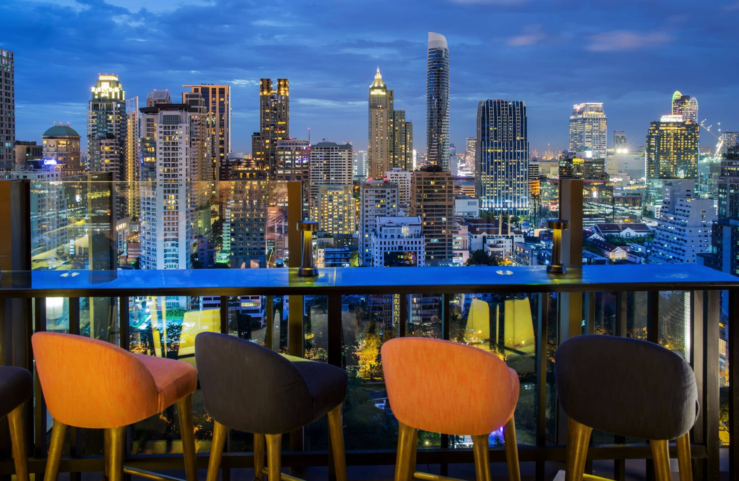 Stilvolle Rooftop-Bar mit Blick auf die beleuchtete Skyline