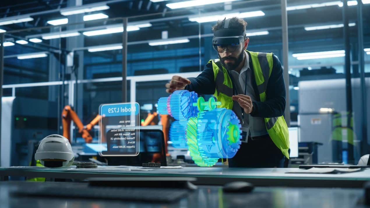 Ingenieur mit AR-Brille in einer modernen Fabrikhalle, simuliert ein Getriebe für einen Elektrokettenzug