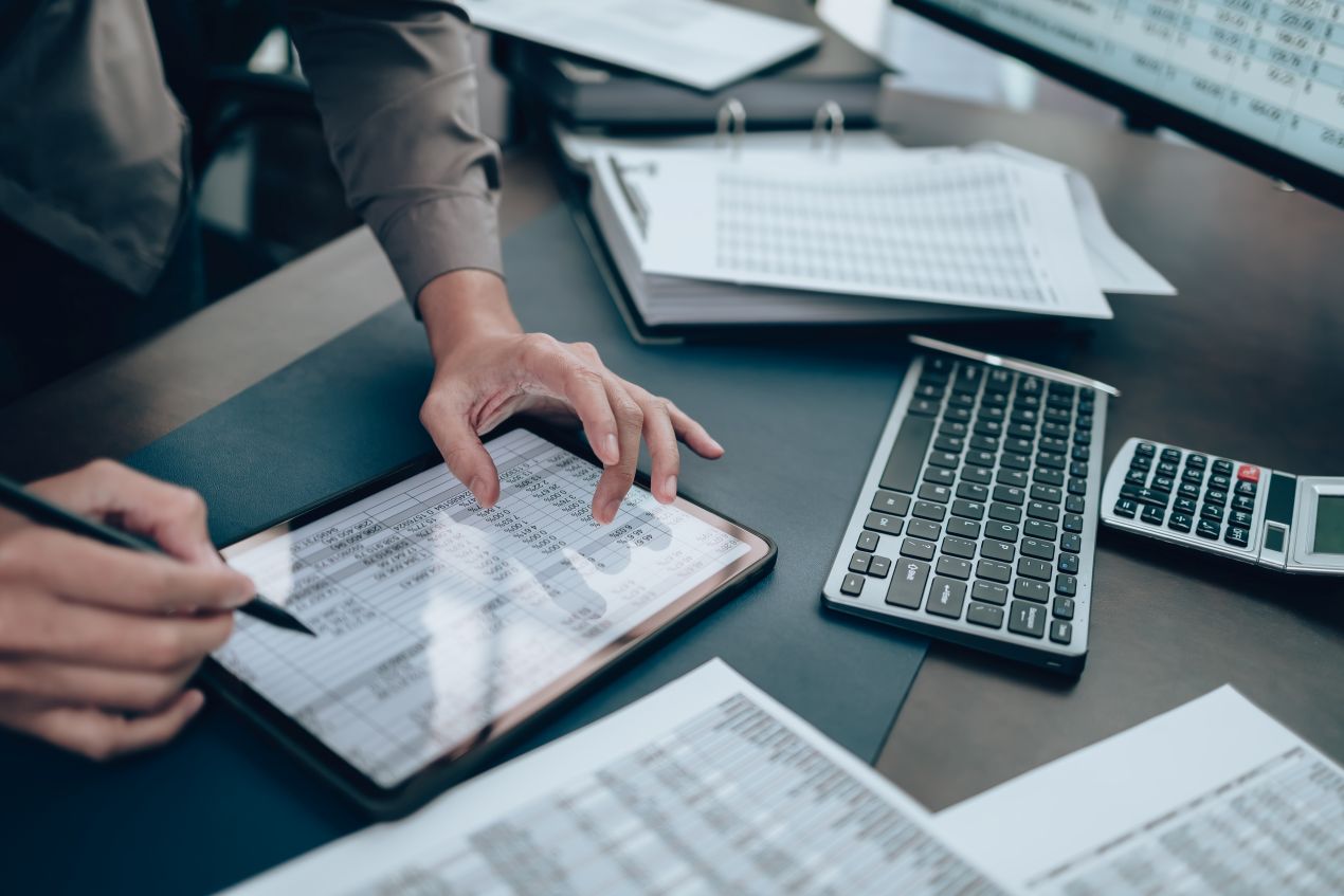 Person arbeitet an digitaler Lohnabrechnung online mit Tablet, Tastatur und Tabellen